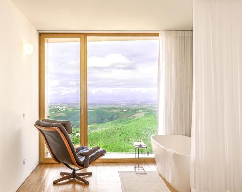 塞亚Casas Da Lapa, Nature & Spa Hotel的一间带椅子、浴缸和窗户的浴室