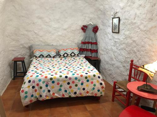 格拉纳达CUEVA EL DUENDE的一间卧室,配有一张床,墙上挂着一连串连衣裙