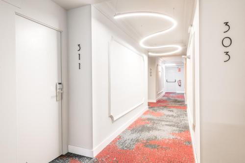 莱里达三思公园酒店的走廊上设有白色的墙壁和红色的地板