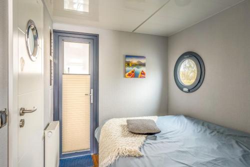 哈特姆Tiny Hanzeboat的卧室配有一张床,墙上挂着一个钟