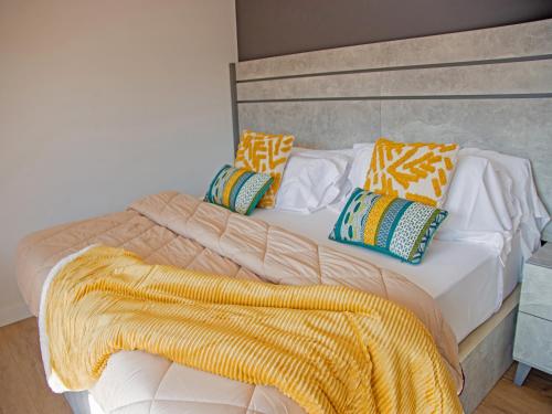 马里亚诺Apartamentos Santander Maliaño Suites 3000的一张带黄色毯子和枕头的床