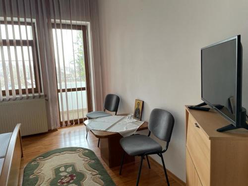 Mînăstirea NeamţCasa de Pelerinaj Ierusalim Hozeva的客厅配有两把椅子、一张桌子和电视