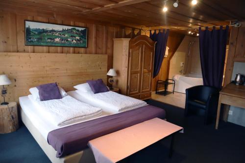 格吕耶尔格鲁耶尔客房酒店的一间卧室配有一张床、一个浴缸、一张床和一张书桌