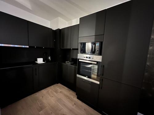 佩皮尼昂Perpignan Vauban magnifique T2 avec balcon的黑色的厨房配有黑色橱柜和微波炉