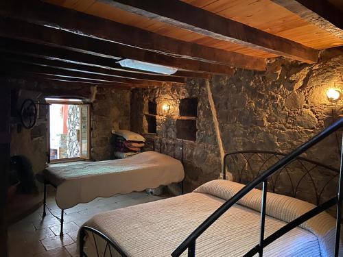 利马索尔Rodous Village House的一间石墙客房内的卧室,配有三张床