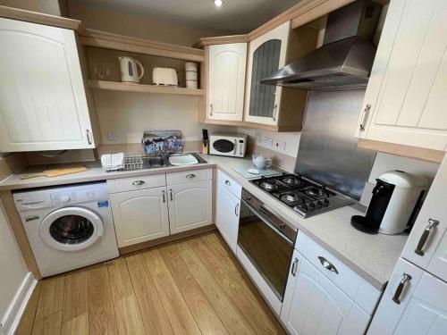 CrontonViking的厨房配有白色橱柜、洗衣机和烘干机