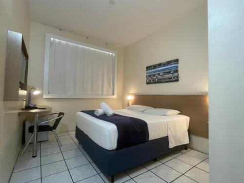 弗洛里亚诺波利斯Hotel de Carvalho的酒店客房配有一张床铺、一张桌子和一张书桌。