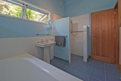 TryphenaFrosty's Retreat - Great Barrier Island Home的带浴缸、水槽和窗户的浴室