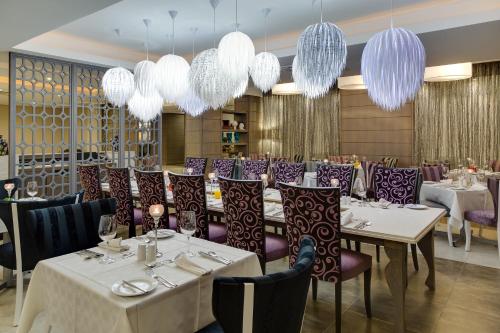 比勒陀利亚ANEW Hotel Hatfield Pretoria的餐厅设有白色桌子、紫色椅子和吊灯