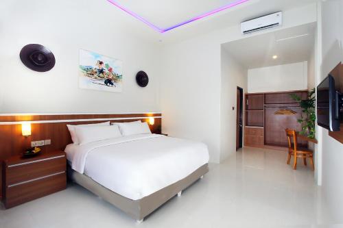 龙目岛库塔The Jumbo Homestay的卧室配有一张白色大床和电视。