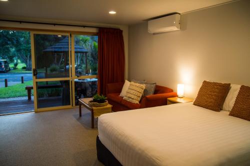哈海Hahei Beach Resort的卧室配有床、椅子和窗户。