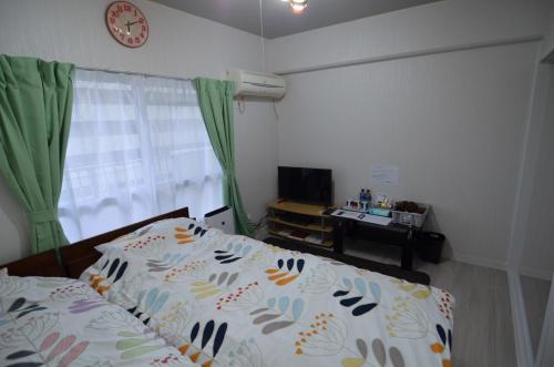 宫崎Amont Nakamura - Vacation STAY 83274的卧室配有一张床,墙上挂着一个钟