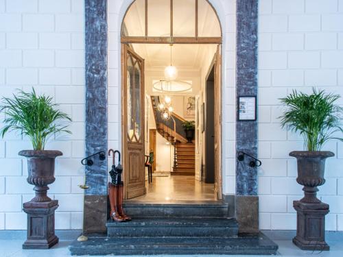 康布雷La Demeure Numéro 5的走廊上设有两棵盆栽植物的开放式门