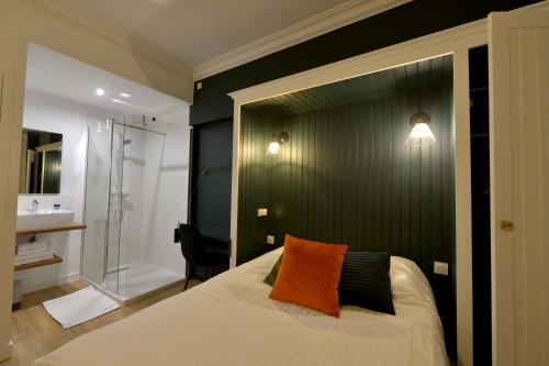 瑟堡Hôtel Le Tiburon的一间卧室配有一张带橙色枕头和淋浴的床