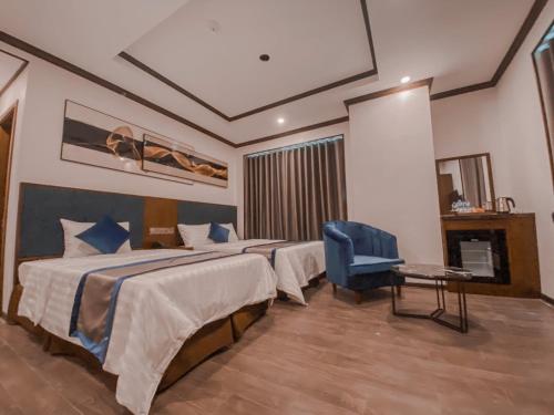 格卢市社Kingdom Hotel Cua Lo的酒店客房,设有两张床和一张蓝色椅子