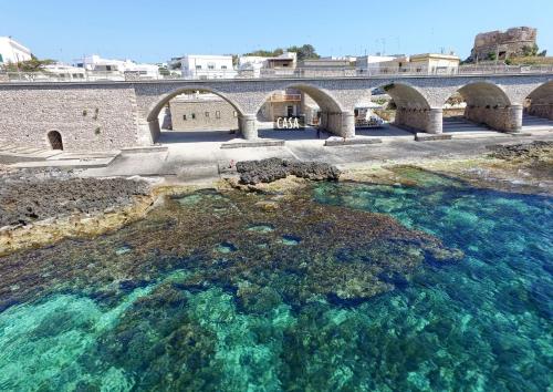 莱乌卡La casa in riva al mare的一座大水体上的老桥