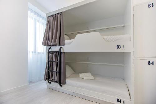 阿尔布费拉Musical Hostel的白色客房内的两张双层床,上面有数字