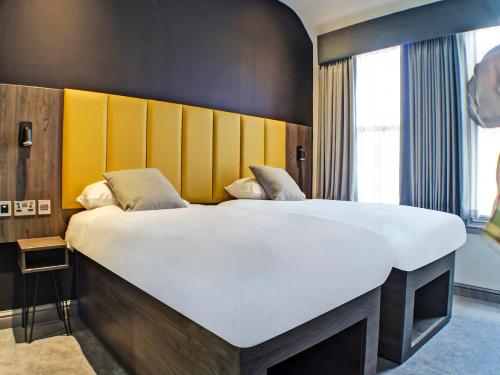 塔姆沃思OYO Tamworth Arms Boutique Pub & Hotel的一间卧室配有一张带黄色床头板的大床