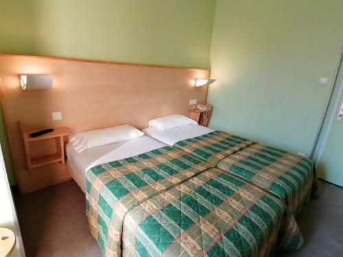 波利尼Les Charmilles的酒店客房,配有一张带绿毯的床