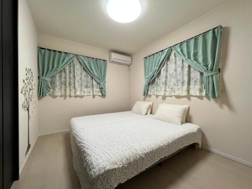 奈良奈良枫宾馆的一间小卧室,配有床和2个窗户