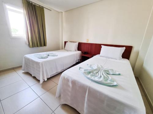 大瓦尔泽亚Cerrados Park Hotel的一间设有两张带白色床单的床的房间