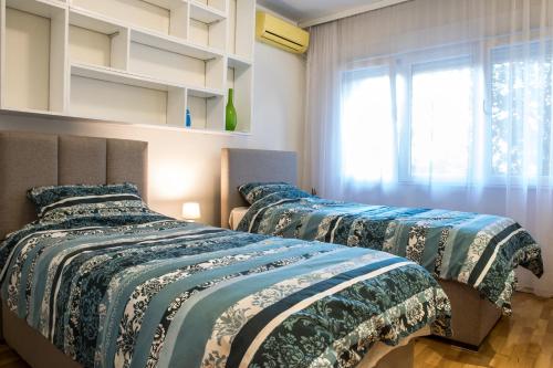 波德戈里察Luxury apartment Podgorica的带窗户的客房内的两张床