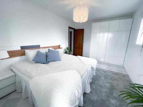 阿利坎特La Zenia Beach House的白色卧室配有一张带蓝色枕头的大床