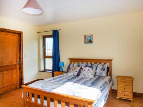 Doogort6 Strand Cottages的一间卧室设有一张木床和一个窗户。