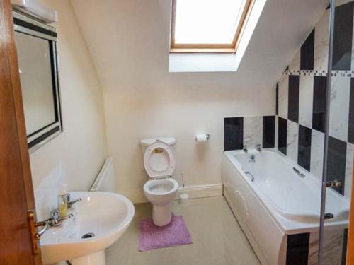 Doogort6 Strand Cottages的浴室配有盥洗盆、卫生间和浴缸。