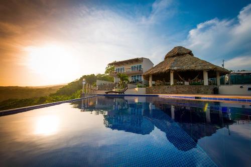 埃尔库科阿尔瓦多洛斯曼戈斯酒店的茅草屋顶的度假游泳池
