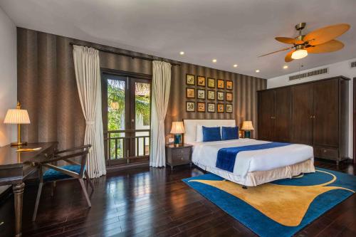 岘港Da Nang Paradise Center My Khe Beach Resort & Spa的卧室配有床、书桌和钢琴