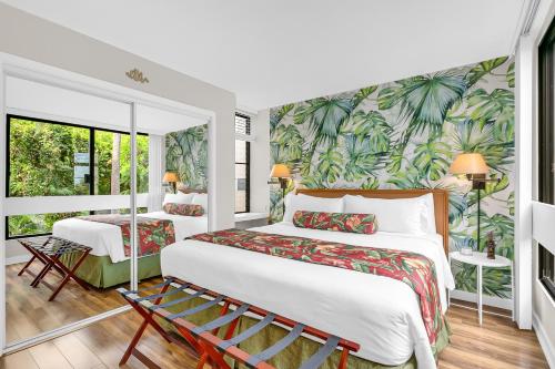 科纳Casa Tropical Kona的配有热带壁纸的客房内的两张床