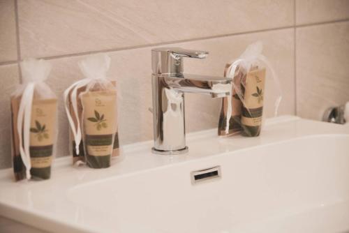 阿格诺Brand New Apartmentcecilia Residence Apt N1的浴室水槽配有水龙头和2瓶肥皂