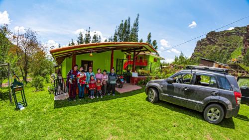 乌鲁班巴Happy Land Valle Sagrado的一群人站在房子前面,坐汽车