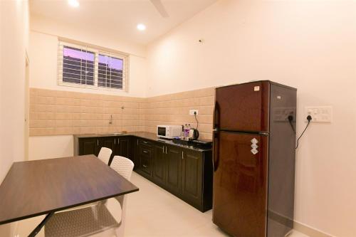迈索尔Xcel Luxury Hotel Apartments-Home Living Redefined的厨房配有黑色冰箱和桌子
