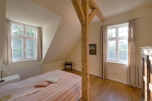 NeuenkirchenFerienwohnung 7 mit Wasserblick, Balkon 2 Pers的一间卧室设有一张床和两个窗户。