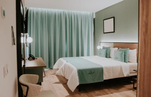 大加那利岛拉斯帕尔马斯Hotel Catalina Plaza Sostenible的一间卧室配有一张带绿色窗帘的床和一张书桌