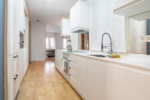 马德里3 bedrooms 2 bathrooms furnished - Salamanca - Stylish - MintyStay的厨房铺有木地板,配有白色橱柜。