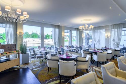 马斯特里赫特马斯特里赫特皇冠假日酒店的餐厅设有白色的椅子和桌子以及窗户。
