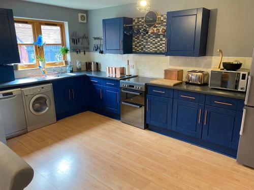 因弗内斯Inverness Holiday House - 2 Bedroom的厨房配有蓝色橱柜、洗衣机和烘干机