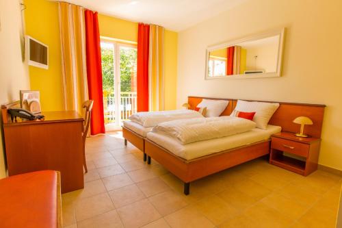 贡特拉姆斯多夫埃利亚酒店的一间卧室配有一张床、一张书桌和一个窗户。