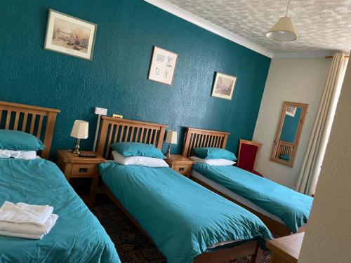 阿姆奇Dinorben Arms Hotel的蓝色墙壁客房的两张床
