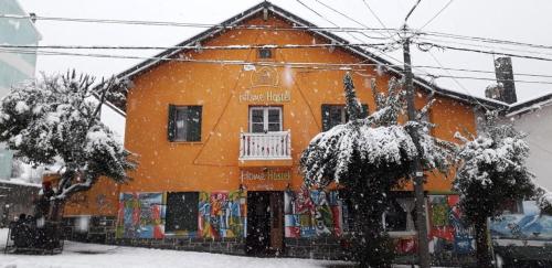 圣卡洛斯-德巴里洛切荷帕之家巴塔哥尼亚旅舍及酒吧的一座橙色的建筑,前面有雪