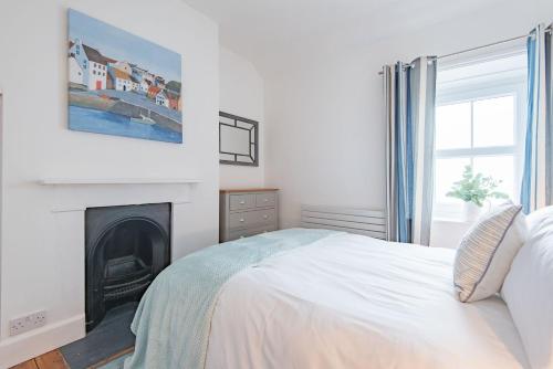 桑盖特Wave Cottage by Bloom Stays的一间白色卧室,配有一张床和一个壁炉