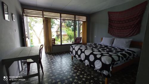 图克图克Leokap Homestay的一间卧室配有一张床、一张桌子和一个窗户。