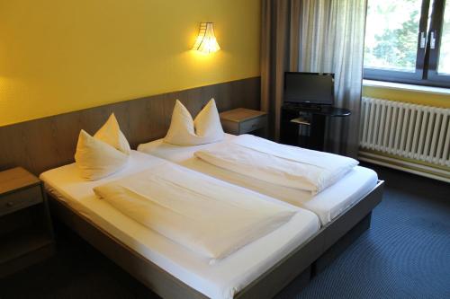 柏林格吕内瓦尔德酒店的一间卧室配有带白色床单和枕头的床。