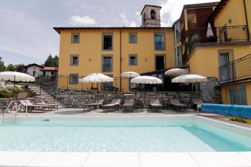 圣费德勒·因特尔维桑塔里贝拉科特酒店的一座带椅子和遮阳伞的大楼前的游泳池