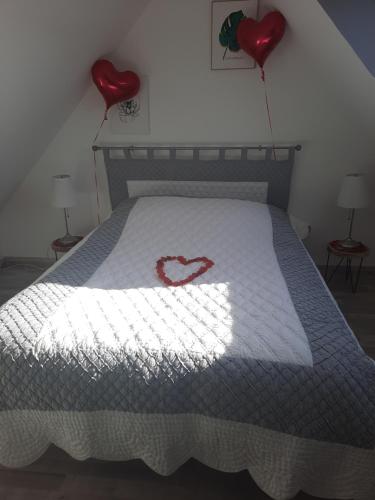 基尔维莱Au bonheur des hirondelles的一张床上有两个红色的心脏气球的床