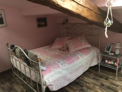 Aigonnayl'Ancienne Forge的一间卧室配有一张带粉红色床单的床,铺有木地板。