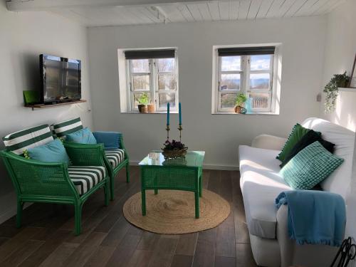 TranekærBeachhouse Langeland的客厅配有绿色椅子和白色沙发